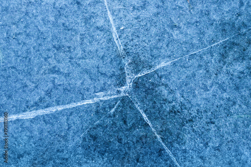 Frozen ice surface with cracks. Blue ice texture background, winter abstract pattern, cold weather concept, natural frozen surface, icy details and frost.