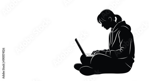 Silhouette of a young person sitting cross-legged on the floor, focused on typing on a laptop computer.