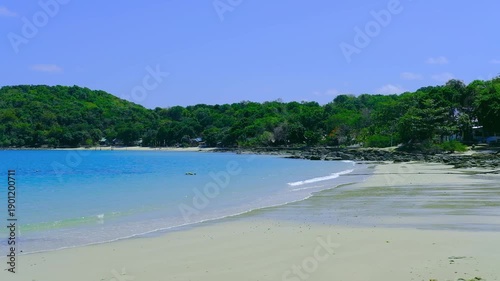 Tropical Beach with Calm Blue Sea and Green Forest, Peaceful Summer Travel Destination.