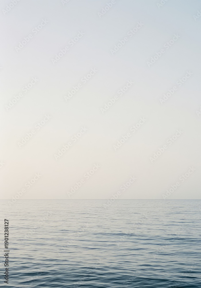 Obraz premium Expansive view of an empty ocean surface meeting a cloudless, pale sky, creating a minimalist, neutral backdrop for design or conceptual projects ,calm ,vast ,infinite
