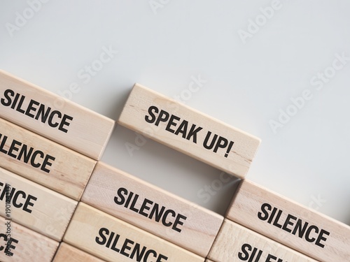 Wooden blocks with the word silence and one block saying speak up concept of breaking the silence and speaking out against injustice or oppression