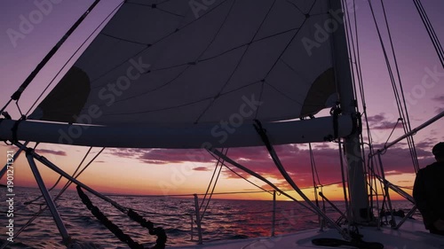 Wallpaper Mural Sailing into Sunset: A sailboat gracefully glides across the tranquil ocean waters, its sails catching the warm hues of a breathtaking sunset. Torontodigital.ca
