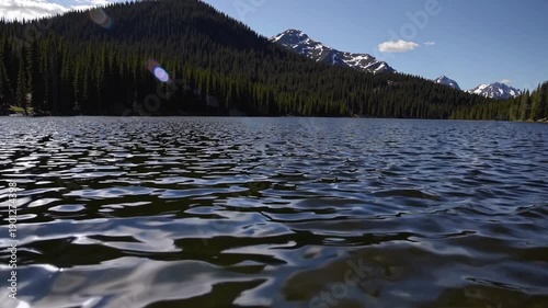 Wallpaper Mural Serene Lake Vista: Capturing the tranquil beauty of nature, a vast lake mirrors the surrounding mountains and verdant trees under a clear, sunlit sky, conveying a sense of peace and serenity.  Torontodigital.ca