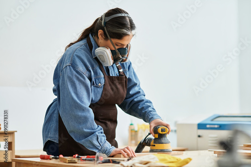 Canvas Print A young woman passionately crafting wood art in a bright workshop