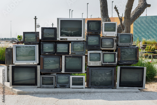 Pile of old cathode ray tube television sets stacked outdoors as art installation.