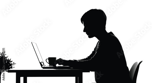 Silhouette profile of a focused person typing diligently on a laptop computer at a dark desk