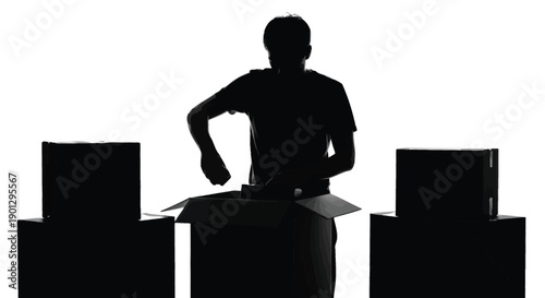 Silhouette of person carefully packing items into an open cardboard moving box surrounded by other packages