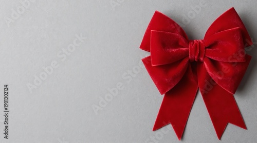 A large red velvet bow on a gray background, perfect for gift wrapping or decoration