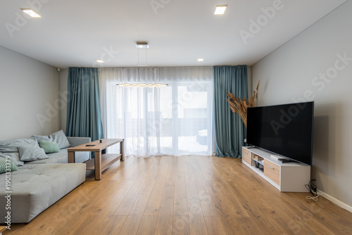 Modern Living Room With Staircase, Wooden Flooring, Natural Light, TV Screen