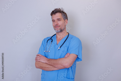 Photos Confident man healthcare professional wearing blue scrubs and stethoscope, arms