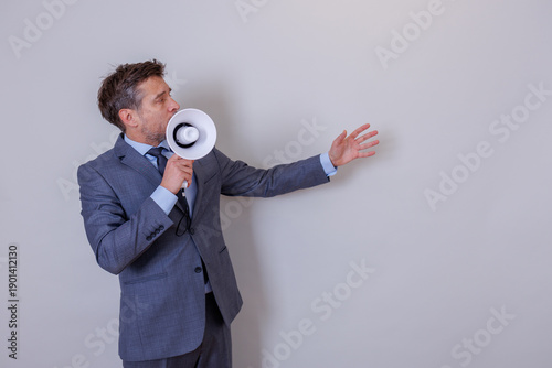 Businessman in suit making a loud announcement with a white megaphone. He is communicating, promoting, and directing public attention