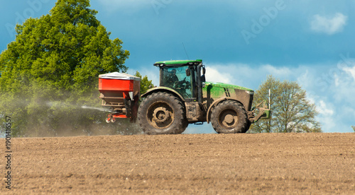Valokuva Tractor spreading fertilizer on farmland