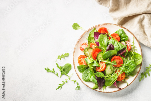 Salad from green leaves and vegetables on white.