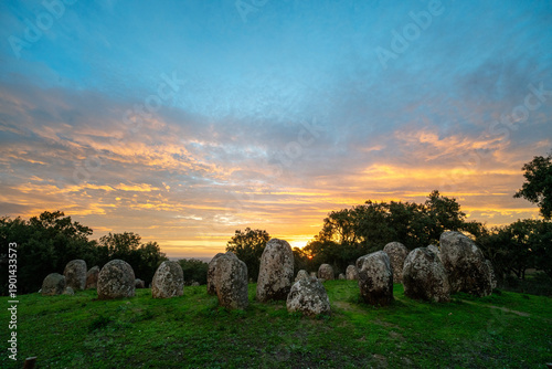 Sunrise at the Cromeleque dos Almendres near Évora, Alentejo, Portugal. An ancient Neolithic stone circle, one of the largest megalithic monuments in Europe, bathed in soft morning light.