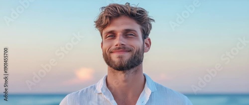 Wallpaper Mural Young man stands on beach with eyes closed and hair blowing in the wind during sunset at the ocean Torontodigital.ca