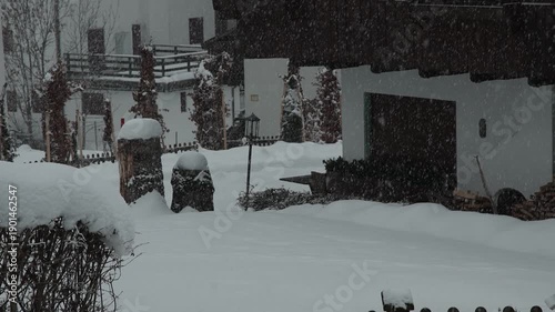 Viseo of snow-covered alpine houses sit quietly during a winter storm. Soft snowfall, muted light, and wooden chalets create a calm, cold, and secluded mountain village mood.