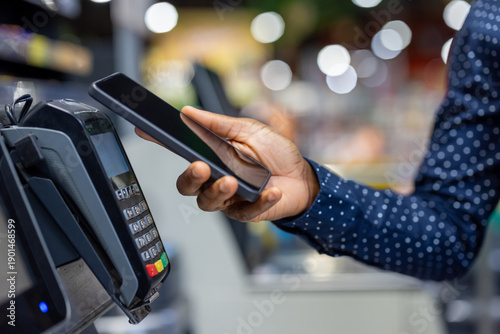 Canvastavla Person using a mobile phone to make a contactless payment at a point of sale ter