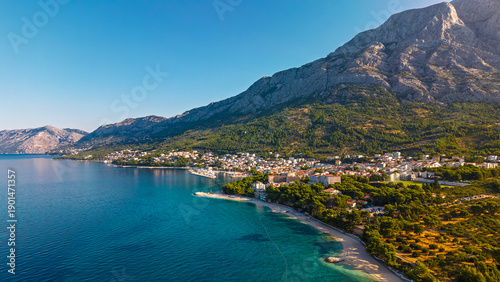 Aerial view of Makarska town on Adriatic coast beneath Biokovo mountains with turquoise sea and beaches