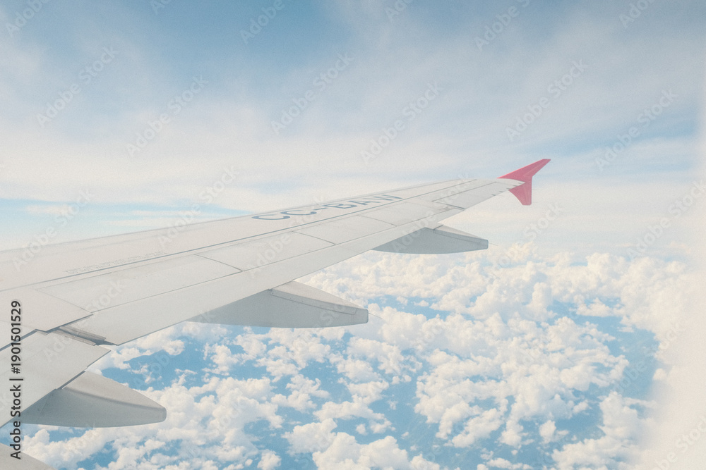 Fototapeta premium Airplane wing view above clouds with clear blue sky