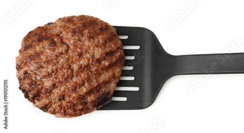 Spatula with delicious grilled meat patty isolated on white, top view