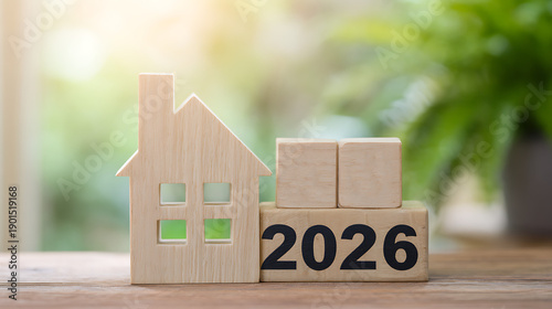 Wooden house model with 2026 blocks on a table with green background