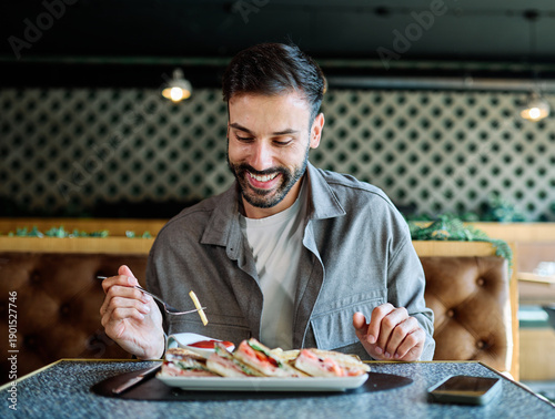 Wallpaper Mural Young man enjoying eating lunch at restaurant Torontodigital.ca