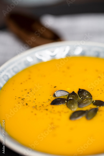 Kürbissuppe in einer Suppenschale auf einem gedeckten Tisch. Nahaufnahmeder Suppe.