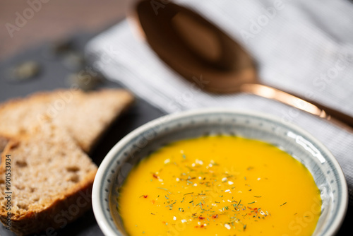 Kürbissuppe in einer Suppenschale auf einem gedeckten Tisch. Nahaufnahmeder Suppe.