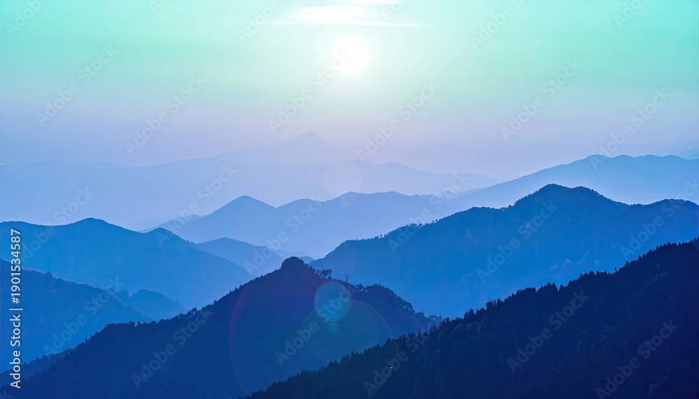 Obraz premium Layered blue mountain peaks fade into a hazy horizon under a pale sun