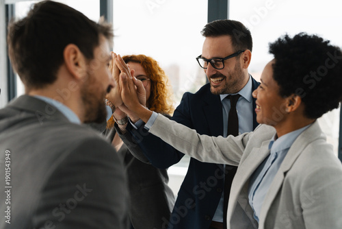 Tableau sur toile A diverse team of successful business professionals celebrating a victory in a modern office