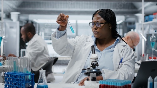 Fotografi Lab materials scientist investigating blue liquid polymer properties in test tube container
