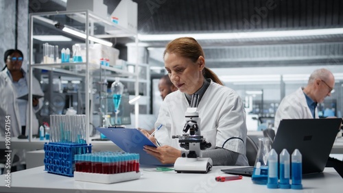 Bild auf Leinwand Histology technician examining pathology slides under microscope in research center