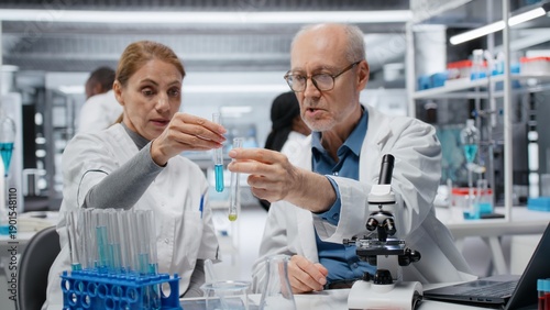Fotografie Lab team leader teaching intern to analyze liquid polymer properties in test tube