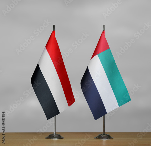 Two table flags of Yemen and Emirates on a blurred gray background