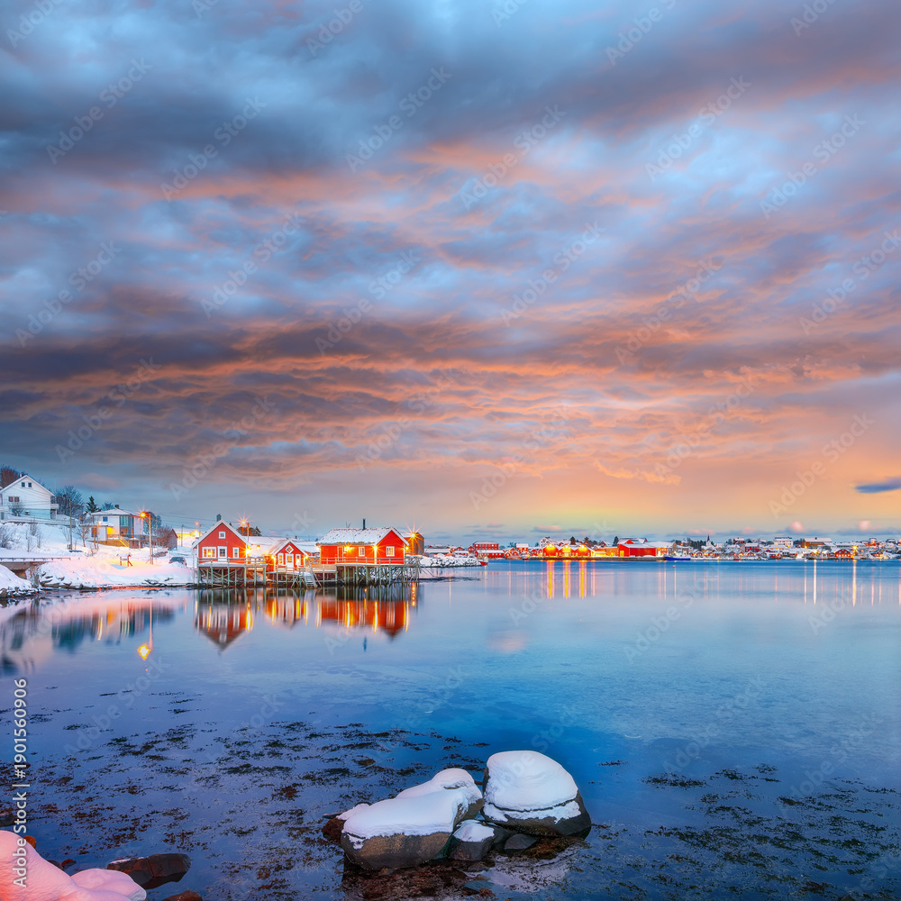 Naklejka premium Outstanding evening cityscape of Reine town. Red rorbuers on the shoore of Reinefjorden.