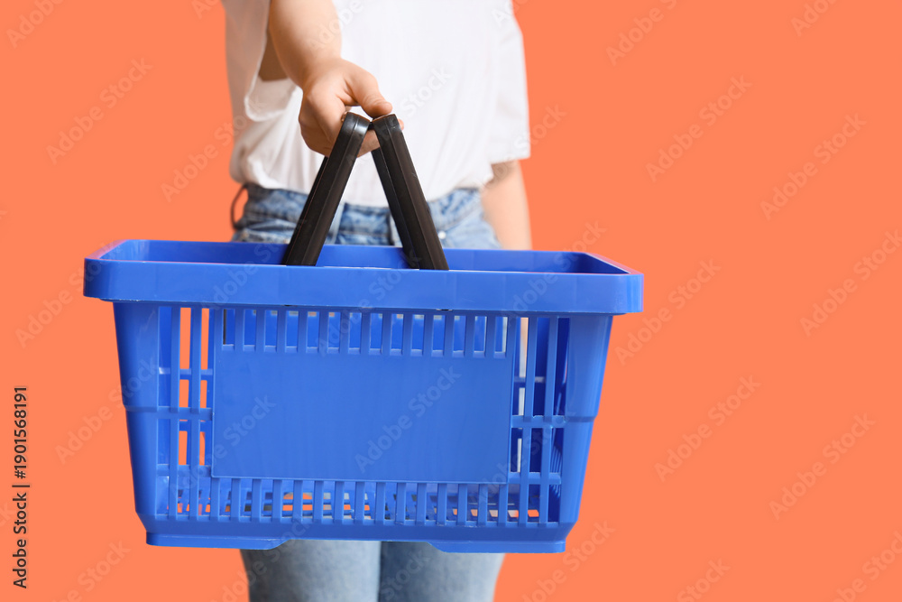 Fototapeta premium Woman with blue shopping basket on orange background