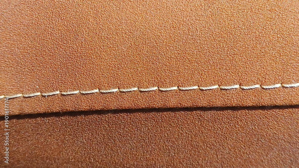 Fototapeta premium Close up of neat white thread stitching on brown synthetic leather. For graphic design, 3D rendering and banners