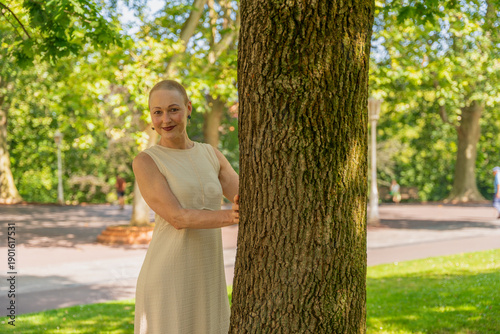 Billede på lærred Woman with shaved head smiling, embracing strength in park