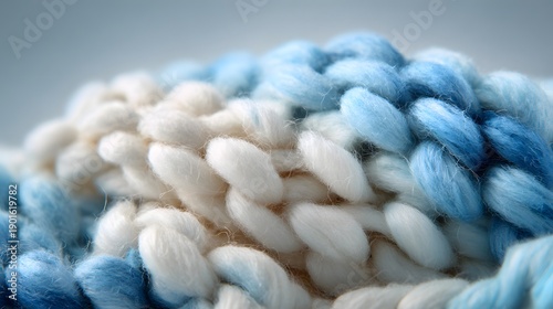 Close-up view of a soft, chunky, hand-knitted blanket in shades of blue and white.