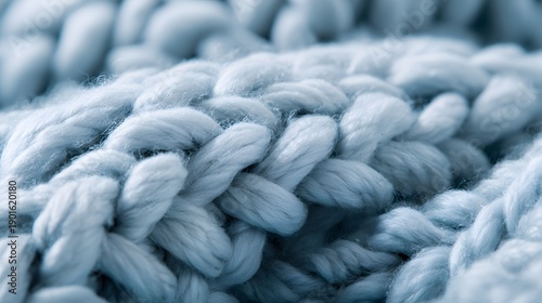 Close-up view of a soft, chunky, light blue knitted blanket, cozy and warm.