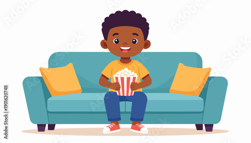 A young boy happily sits on a blue couch, holding a bucket of popcorn, ready to enjoy a movie or show