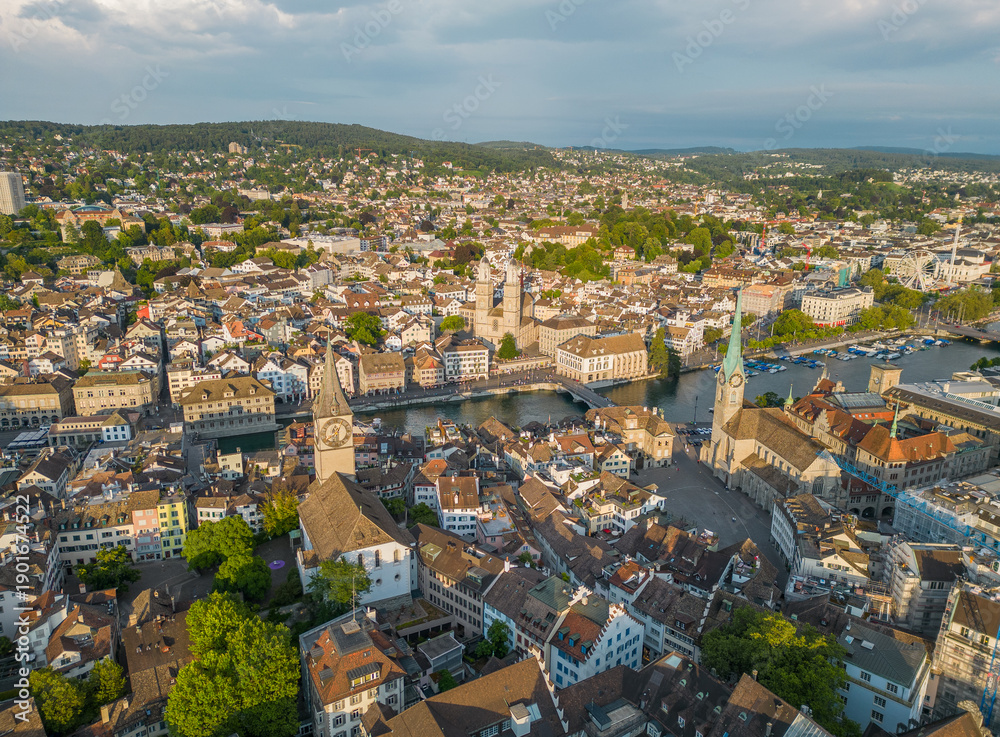 Fototapeta premium High angle aerial view of Zurich old town highlighting Fraumunster, Grossmunster and St Peter Church beside the Limmat River with Lake Zurich during a clear summer day in Switzerland