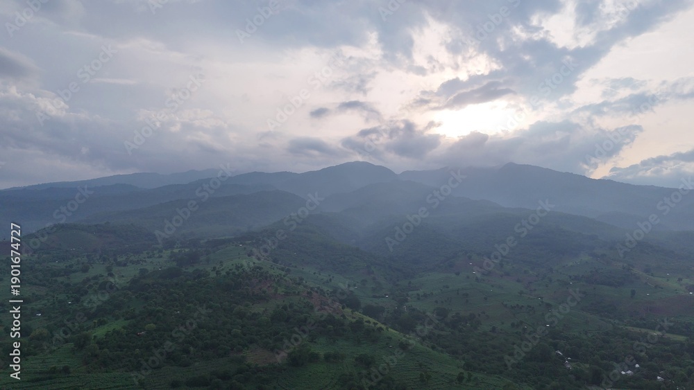 Fototapeta premium Serene Green Mountain Landscape with Hazy Valleys Under Cloudy Sky