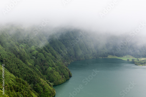 Wallpaper Mural Volcanic crater lake surrounded by dense fog and green forest in Sete Cidades, San Miguel, Azores. Misty atmosphere with caldera views and serene water. Torontodigital.ca