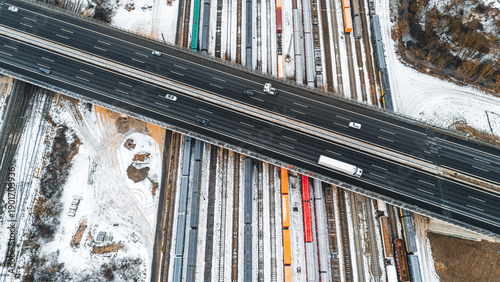 Obraz na plátně High angle drone view of a winter railway yard with freight trains and a motorwa