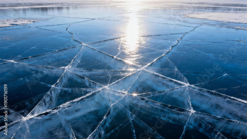 Frozen water surface with geometric cracks under sunlight illumination