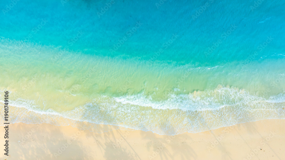 Obraz premium Top view show waves crashing onto a tropical coastline with crystal-clear blue waters contrasting with sandy beaches and coral reefs off the shore of a tropical island with emerald-green waters. 