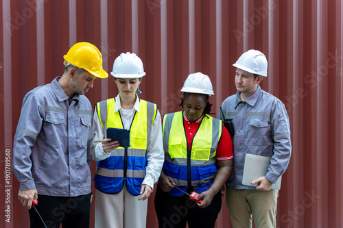 Wallpaper Mural Four Industrial workers wearing safety helmets and reflective vests reviewing data on a tablet in front of cargo container Torontodigital.ca