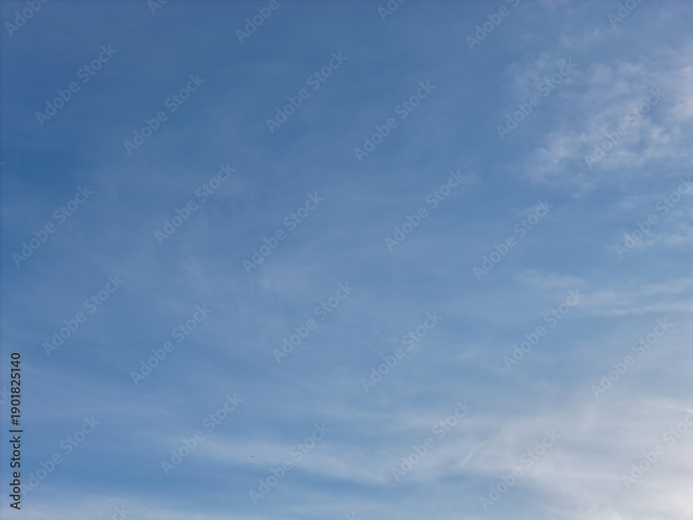 Obraz premium Blue sky and soft, wispy cirrus clouds drifting across the clear atmosphere, creating a serene and expansive natural background for composite work and design elements