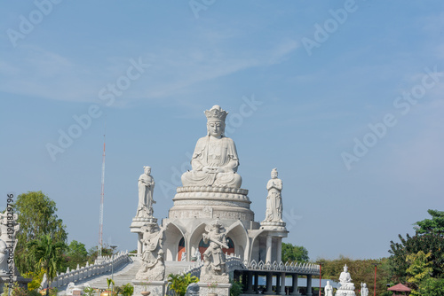 Grand Chinese Buddha statue atop temple staircase under clear blue sky, serene spiritual landmark in Thailand